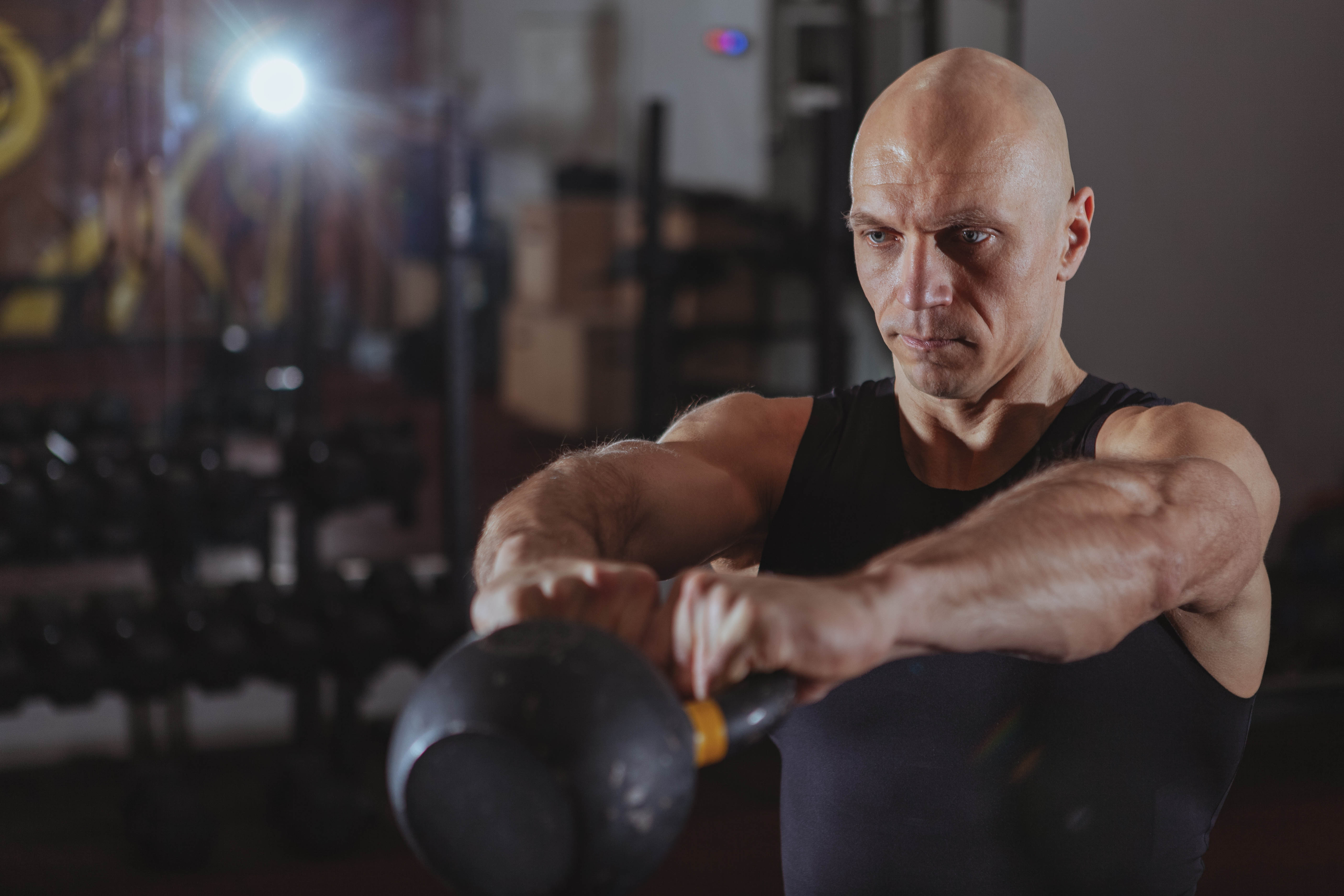 Older man swinging a kettlebell directly in front of his body Older man swinging a kettlebell directly in front of his body
